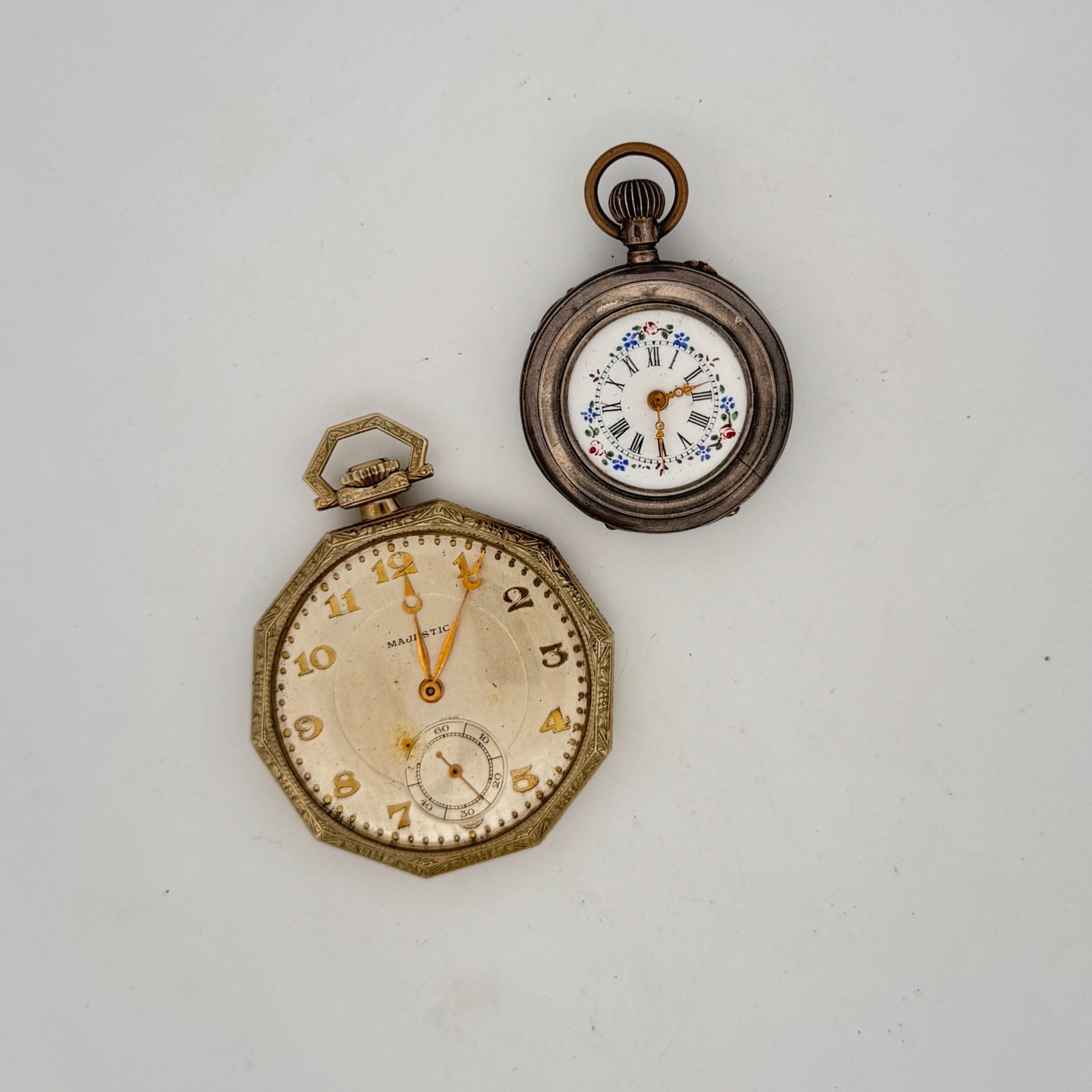 Two Vintage Pocket Watches: A collection of two vintage pocket watches. One is a silver-tone watch with an octagonal case, featuring Arabic numerals and a sub-dial. The second is a smaller, round silver-tone watch with a