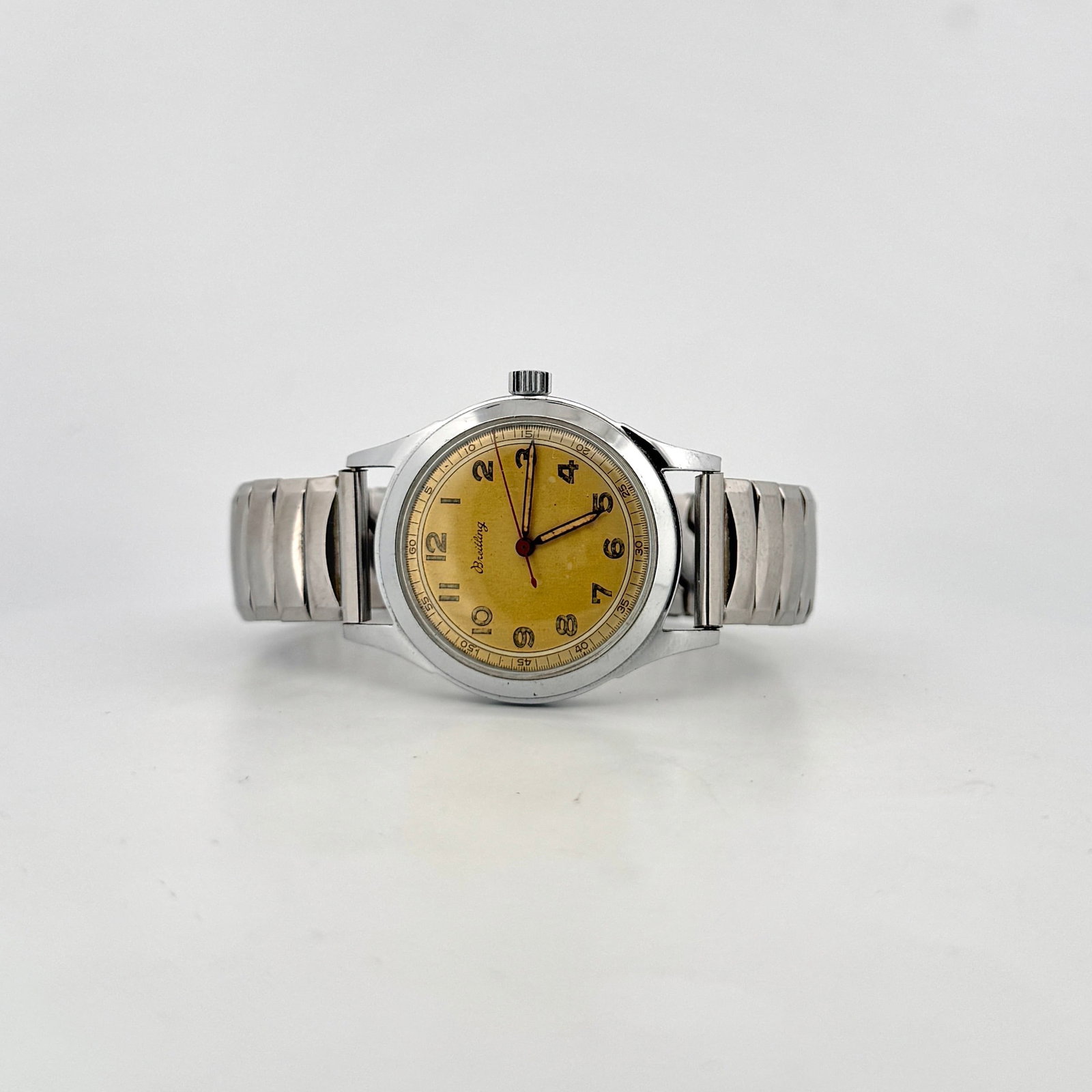 Vintage Breitling Stainless Steel Men's Watch: A vintage Breitling men's watch with a stainless steel case and band. The watch features a yellow dial with Arabic numerals and hands. The movement is visible through the case back and appears to