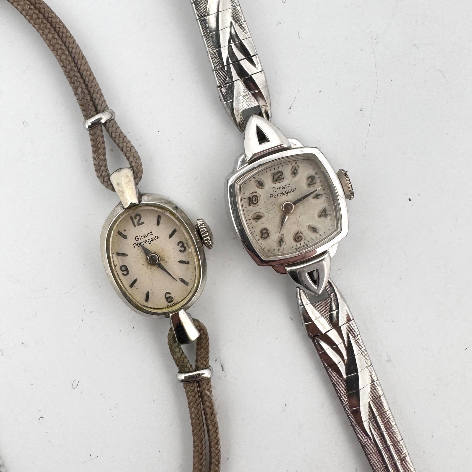 Two Vintage Ladies' Wristwatches: Girard-Perregaux: A collection of two vintage ladies' wristwatches. One is a Girard-Perregaux with an oval face and a fabric strap, measuring approximately 4 inches in length. The second is a Girard-Perregaux 