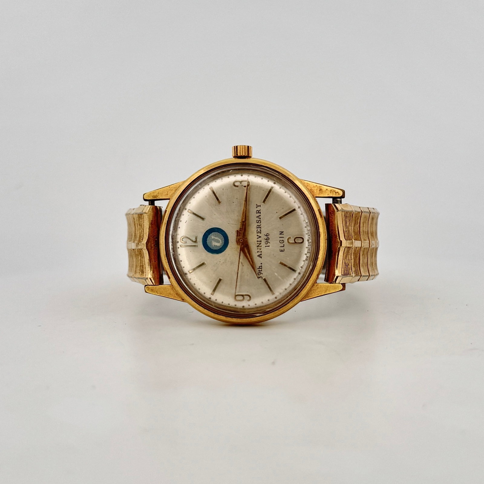 Elgin 39th Anniversary 1966 Gold-Tone Watch: This vintage Elgin watch commemorates the 39th Anniversary in 1966. It features a gold-tone base metal bezel, a stainless steel back, and a manual wind movement with 17 jewels. The dial has a unique b