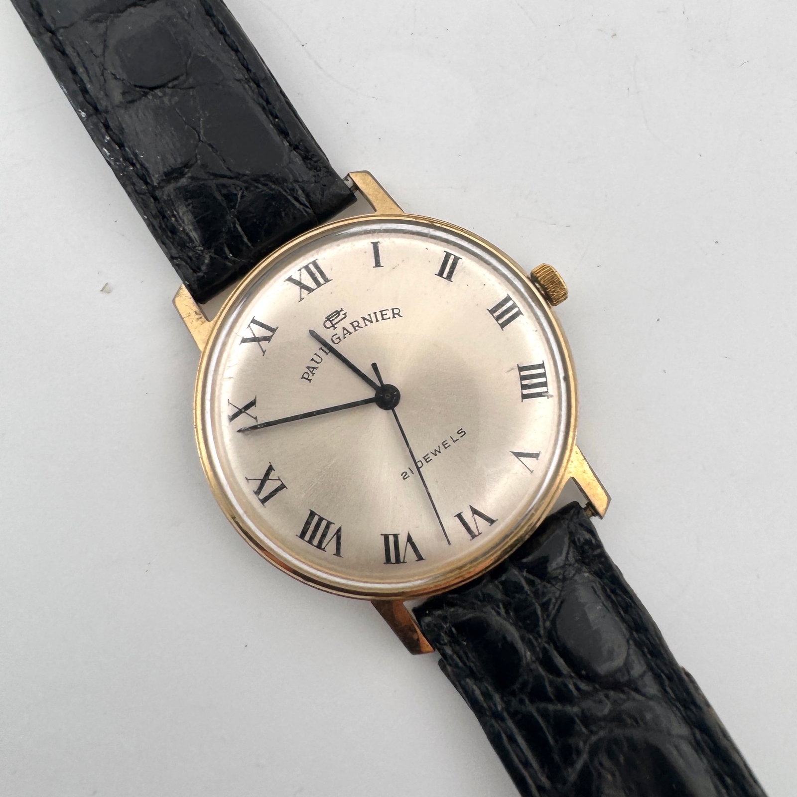 Paul Garnier 21 Jewels Manual Wind Watch with Black Leather Strap: A vintage Paul Garnier manual wind wristwatch featuring a silver dial with Roman numerals and a black leather strap. The watch has 21 jewels and a base metal bezel with a stainless steel back. The mov