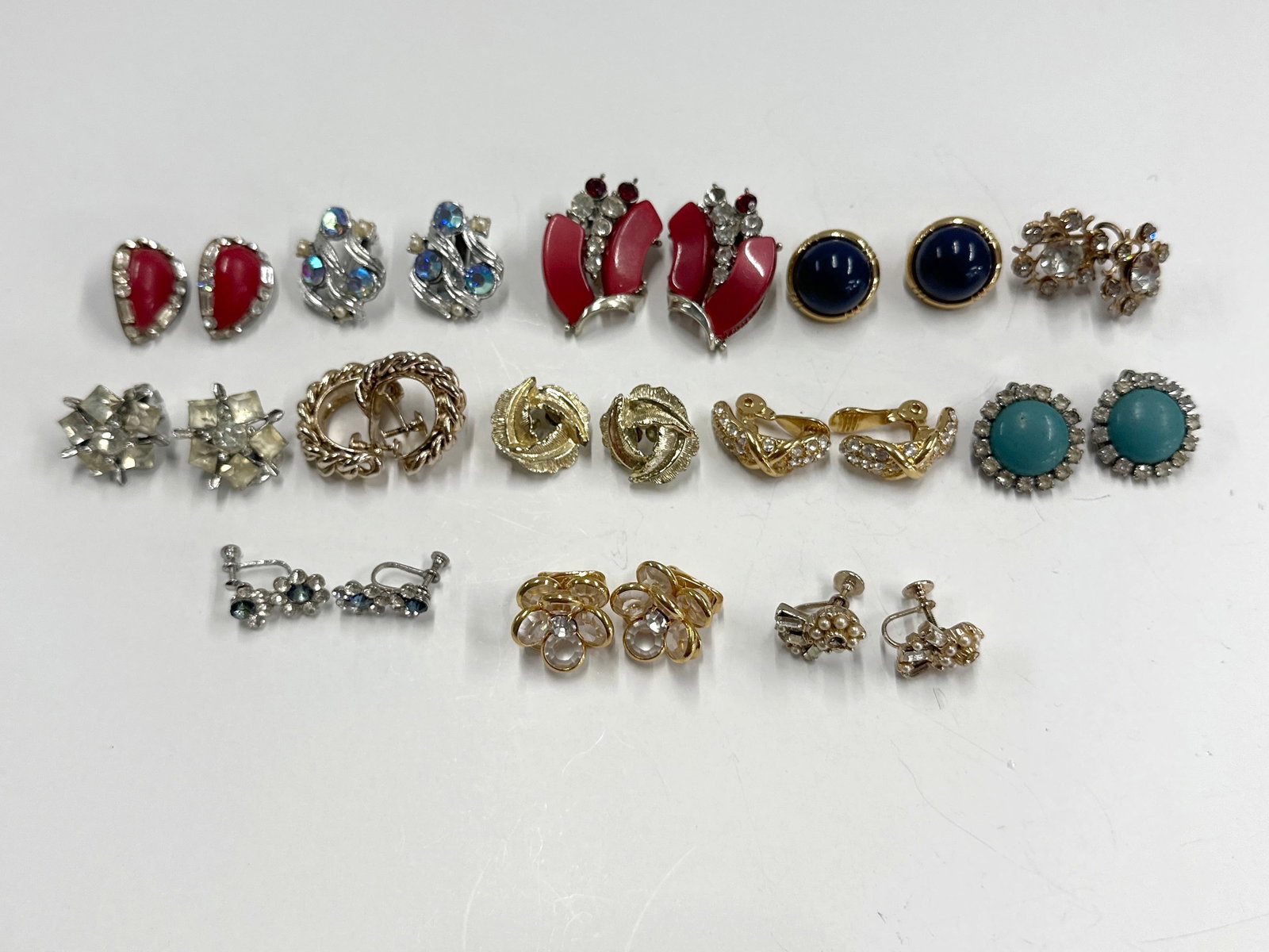 13 Pairs of Vintage Costume Earrings: A collection of assorted vintage costume earrings, including clip-on and screw-back styles. Features various designs, colors, and materials, such as faux pearls, rhinestones, and enamel accents. Some 
