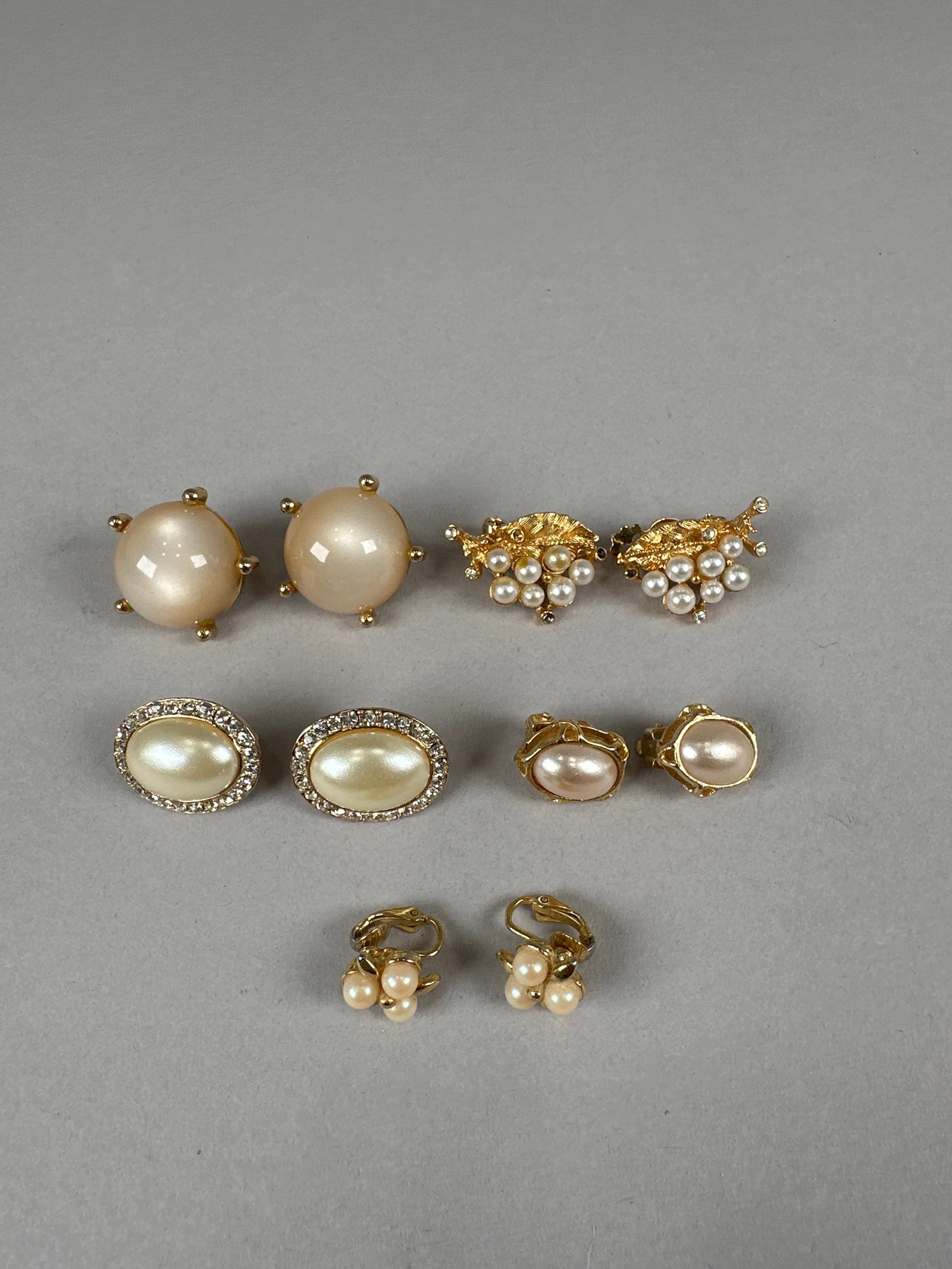 Collection of Assorted Vintage Earrings: A collection of 5 pairs of vintage earrings, including pearl-style studs, ornate gold-tone floral designs, oval faux pearl and more. Some pieces appear to be clip-on. Weight: 52g. Dimensions: 1&#