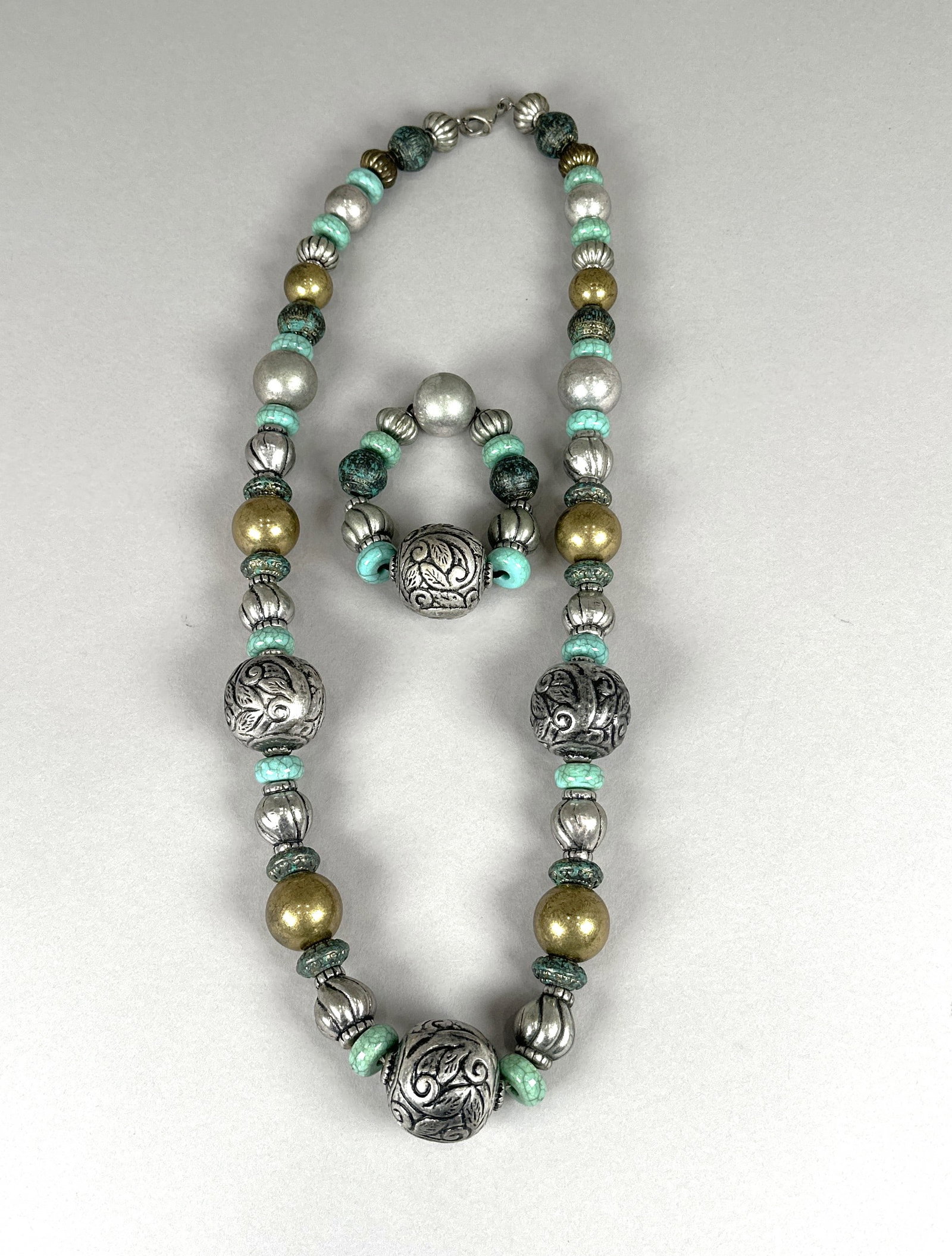 Tibetan Style Necklace and Bracelet Set with Turquoise and Silver Beads: A striking set featuring a long necklace and a matching bracelet, both adorned with a variety of intricately designed beads. The set incorporates large, ornate silver-tone spherical beads with swirlin