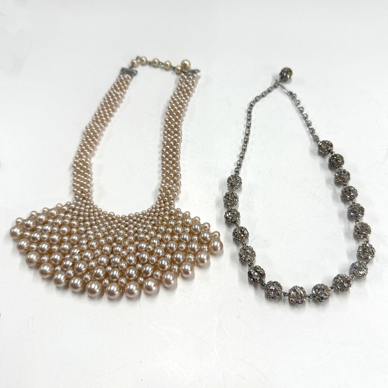 Vintage Faux Pearl and Rhinestone Necklace Pair: A set of two necklaces. The first is a statement necklace featuring a fan of graduated faux pearls. The second is a delicate chain necklace adorned with sparkling crystal balls. Weight: 102g. Longest 
