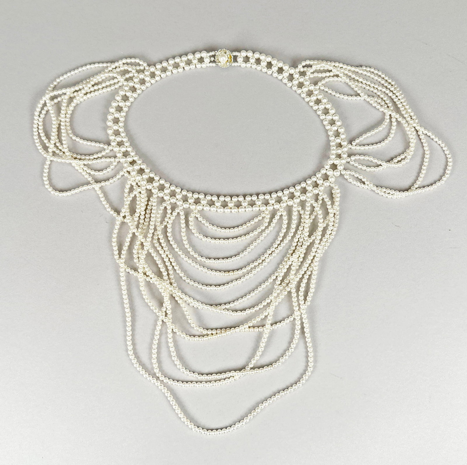 Vintage Multi-Strand Faux Pearl Necklace: This vintage necklace features multiple strands of small, lustrous faux pearls. The intricate design cascades down, creating a dramatic effect. The clasp is marked "JAPAN", indicating its or