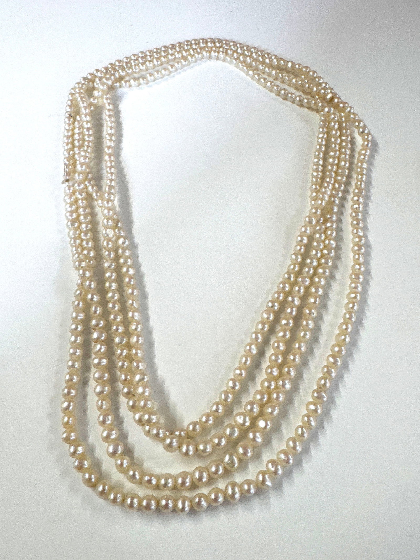 Multi-strand Pearl Necklace with Gucci Pouch: A delicate multi-strand necklace featuring numerous small, lustrous pearls. The necklace appears to be strung on thread, with a visible knot and fraying on one strand, indicating it may need restringi