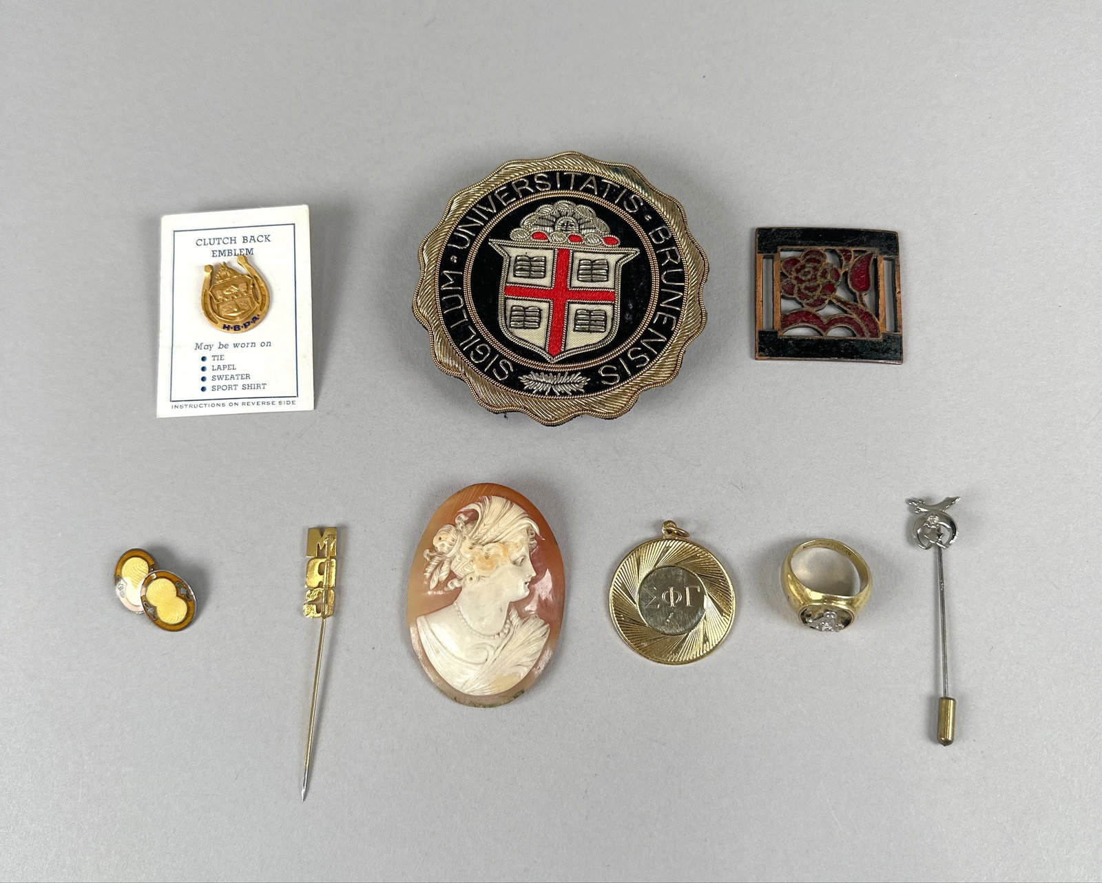 Collection of Assorted Vintage Jewelry and Accessories: This lot features a collection of vintage jewelry and accessories, including a cameo brooch, a Brown University crest pin, a gold-tone ring, a tie tack, cufflinks, and other decorative pins and pendan