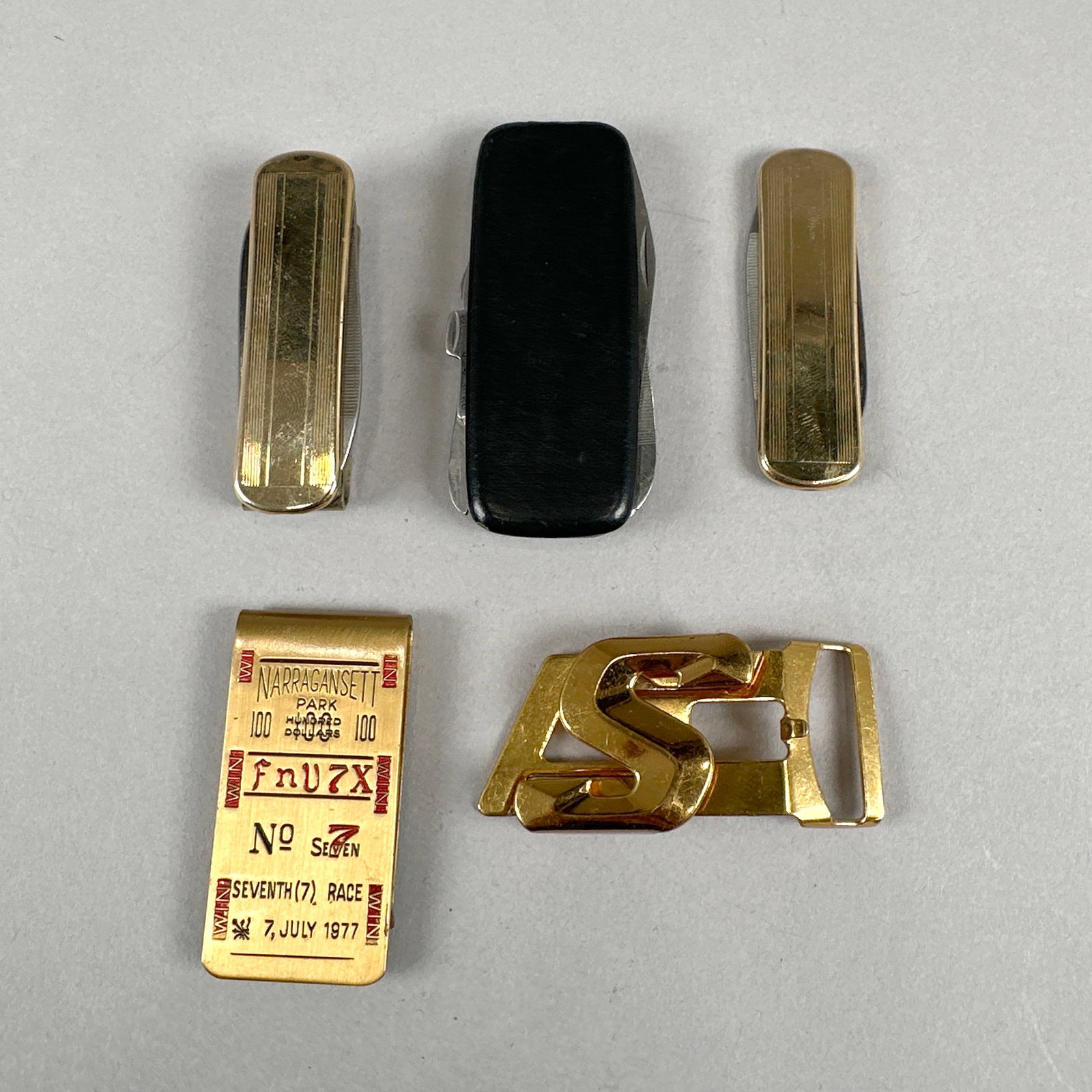Money Clips & Pocket Knives: This lot includes a multi-tool pocket knife with various implements, two smaller folding knives (one marked 'Imperial Stainless'), a gold-tone belt buckle with an 'S' initial (marked &