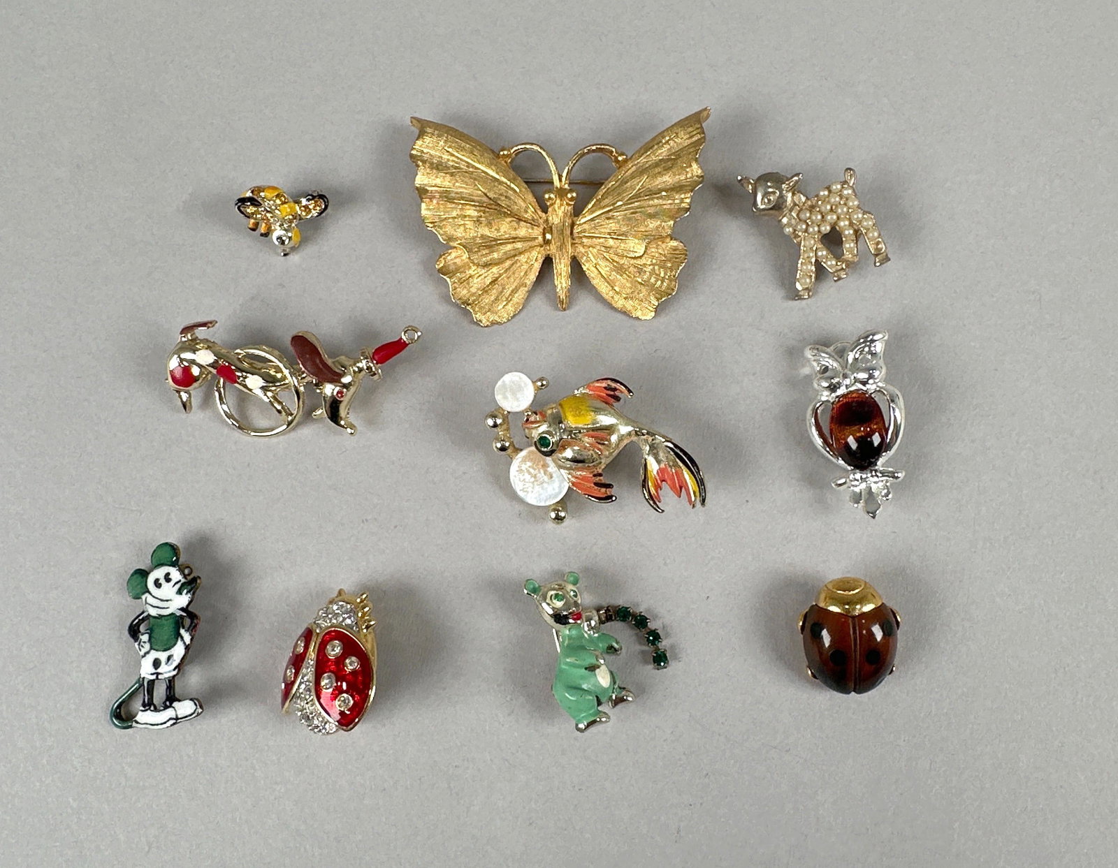 Ten Animal Pins/Brooches: A collection of ten vintage brooches featuring various designs including animals, insects, and characters. Materials appear to be gold-tone metal, enamel, and rhinestones. Some pieces are signed