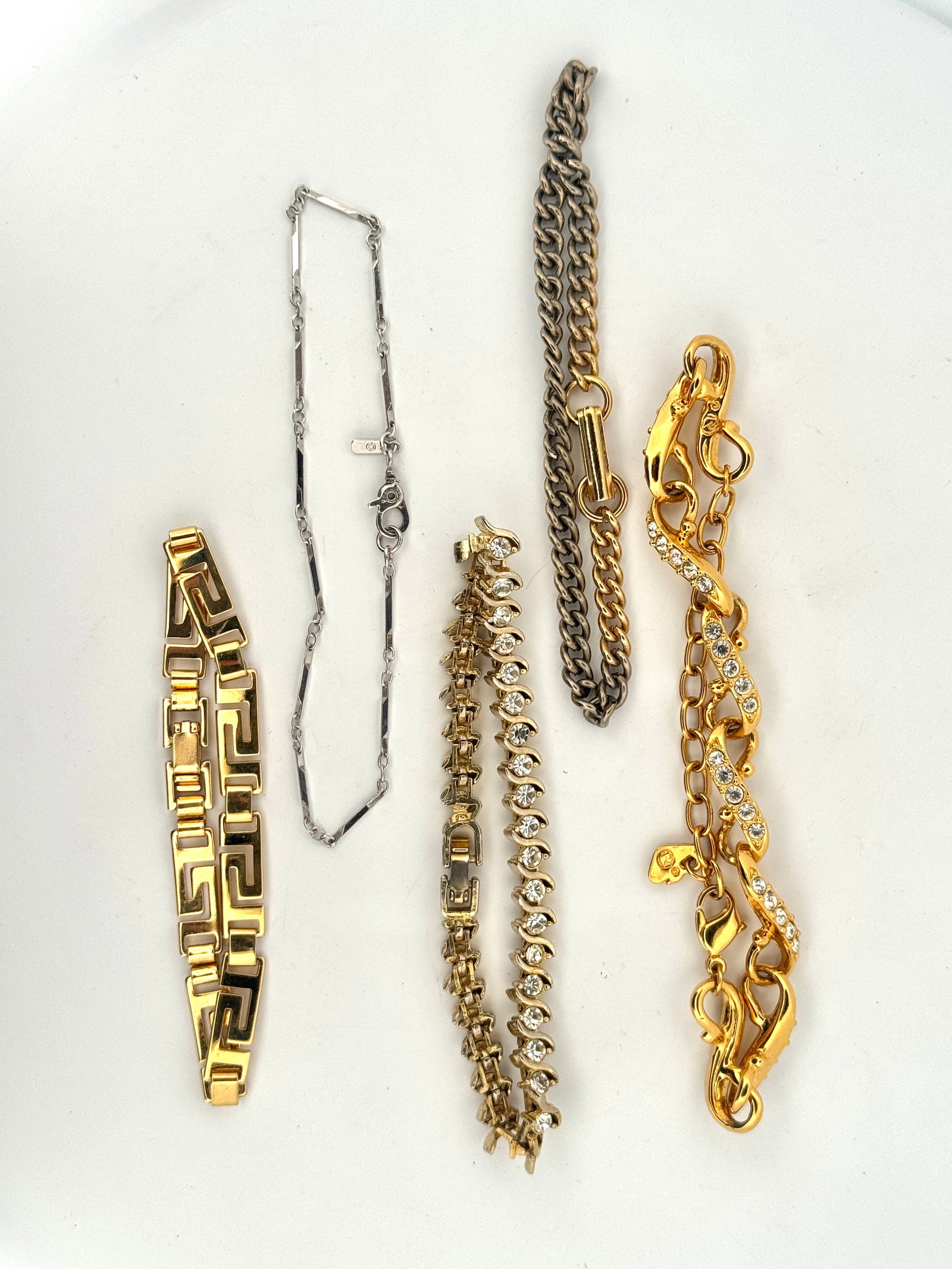 Five Bracelets: A collection of costume jewelry including several bracelets in gold and silver tones, some with rhinestone accents, and a delicate silver-tone necklace. Styles vary from chunky chains to delicate