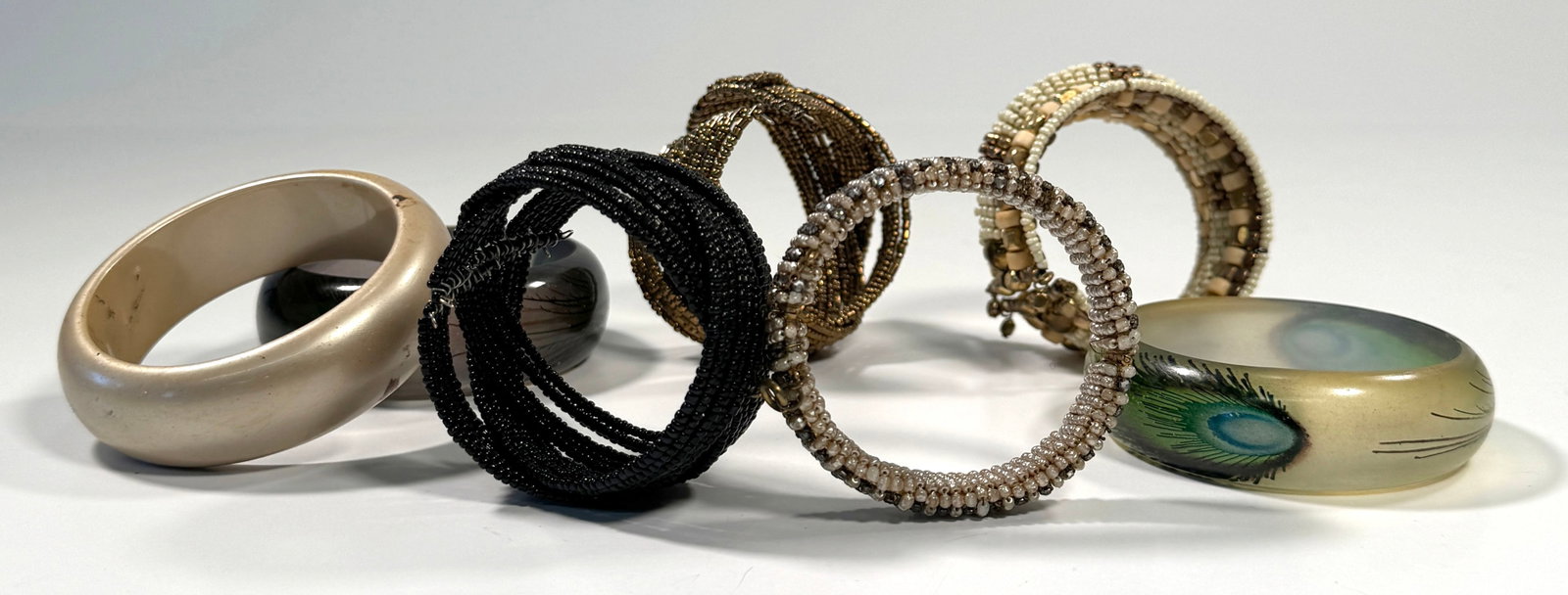 Seven Lucite & Beaded Bangles: Lot of seven assorted bracelets. Includes beaded, resin, and other materials in various colors and styles. A diverse collection for any jewelry enthusiast.