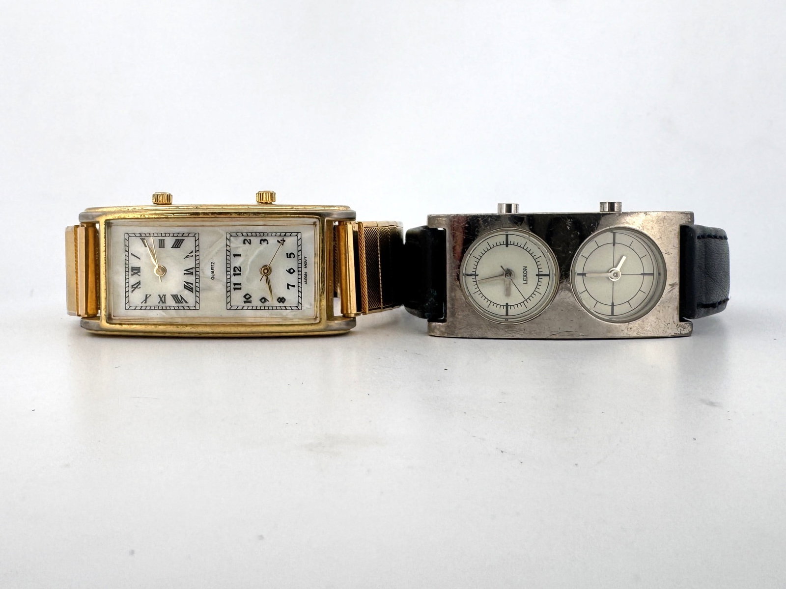 Two Dual-Dial Wristwatches: Gold-Tone and Stainless Steel: This lot features two dual-dial wristwatches. The first is a gold-tone watch with a white face, Roman numerals on one dial, and Arabic numerals on the other. It has a gold-tone expansion band. The sec