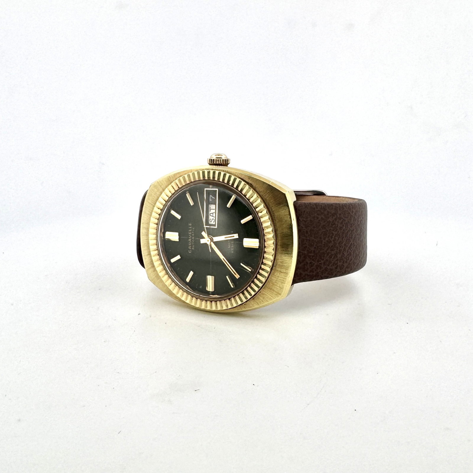 Caravelle Automatic Gold-Tone Watch with Green Dial and Day/Date Function: This vintage Caravelle automatic watch features a striking green dial with gold-tone hour markers and hands. The watch is housed in a gold-tone case with a fluted bezel and is fitted with a brown leat