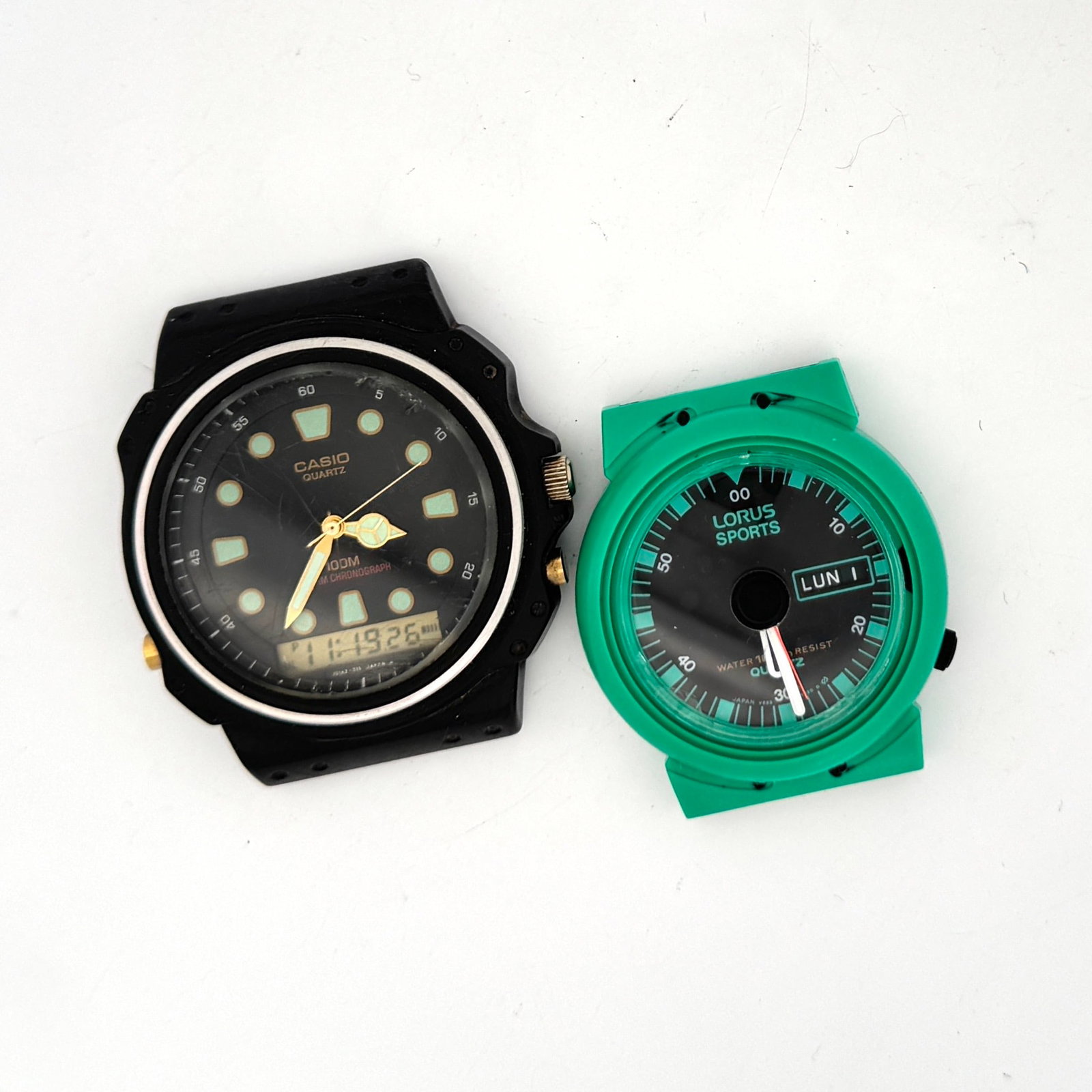 Casio 100M Alarm Chronograph Quartz Watch and Lorus Sports Watch: This lot includes a Casio 100M Alarm Chronograph Quartz Watch with an analog and digital display, and a Lorus Sports watch with a green case and day/date display. The Casio watch has a black case.&nbs