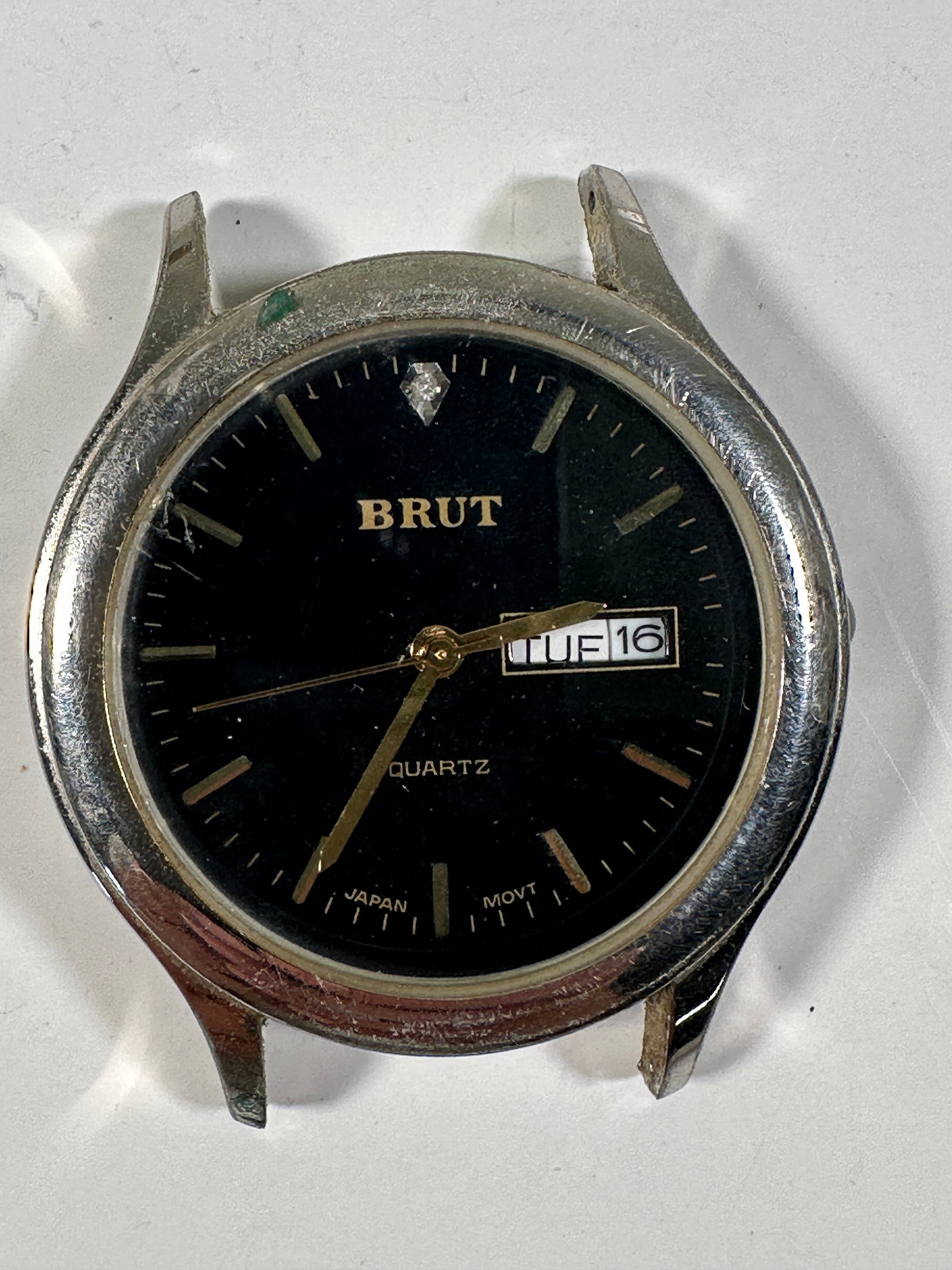 Brut Quartz Wristwatch with Black Dial - No Band: Brut quartz wristwatch with a black dial, date window, and stainless steel back. Japan movement. The watch is being sold without a band. Weight: 1oz. Size: 1.75'' long. 
