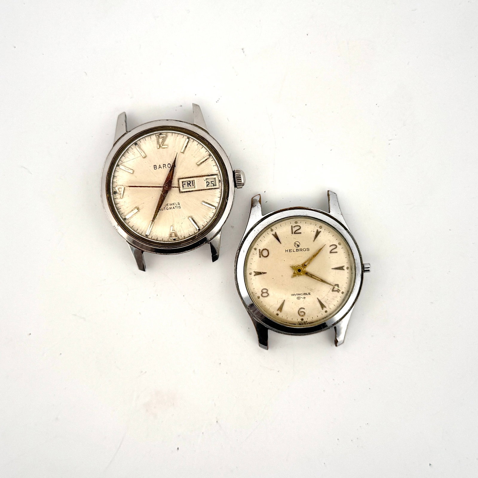 Two Vintage Wristwatches: Baron Automatic and Helbros Invincible: A collection of two vintage wristwatches. The first is a Baron automatic watch with a day-date complication. The second is a Helbros Invincible with a manual wind movement. Both watches feature cream-