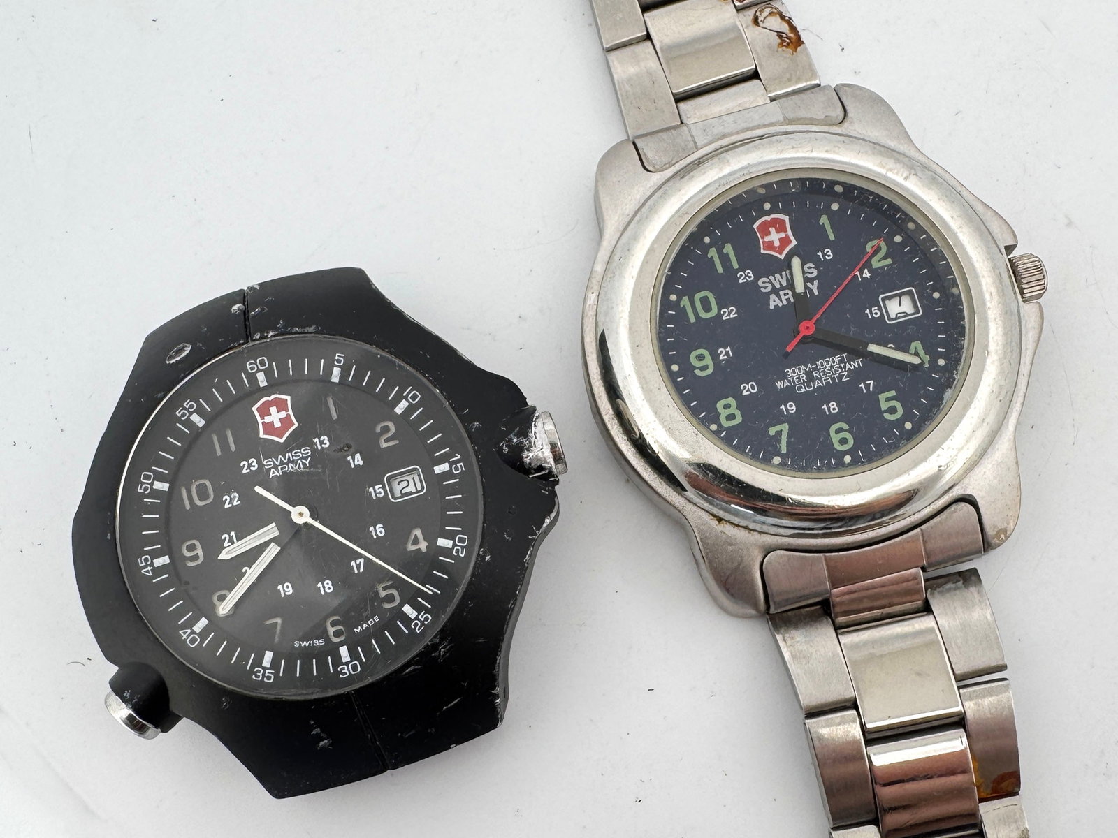 Two Swiss Army Wristwatches: Two Swiss Army wristwatches. One with a stainless steel band and blue face, the other with a black band and black face. Both appear to be in used condition. Weight: 4.9oz. Largest one when closed: 4&#