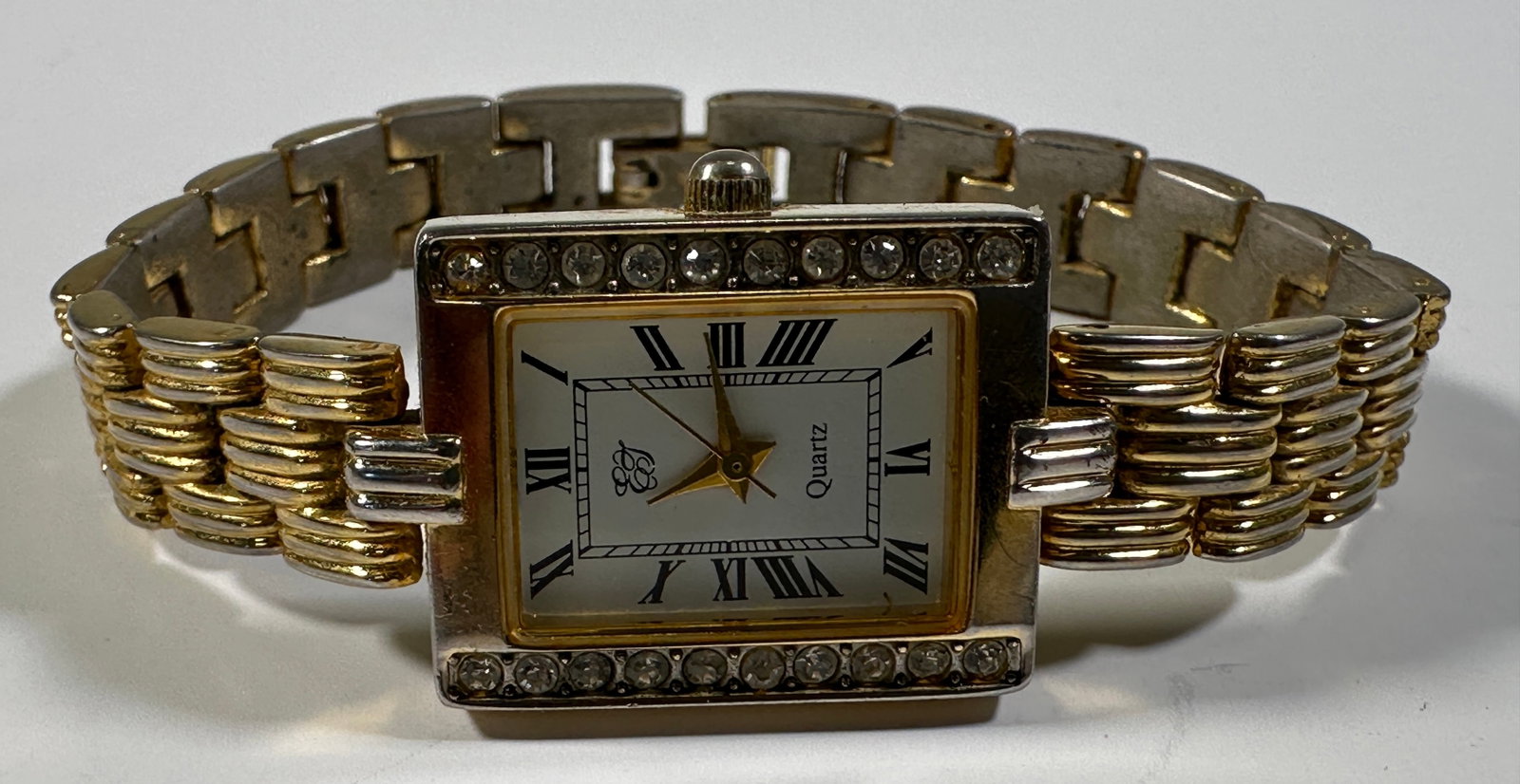 Ladies' Two-Tone Quartz Wristwatch with Rhinestones: Ladies' two-tone wristwatch. The watch features a rectangular face with Roman numeral markers and a rhinestone-set bezel. The band is a combination of gold and silver tones. Weight: 1.3oz. Size: 0