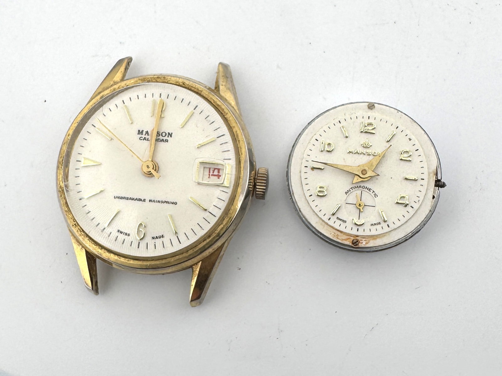 Two Vintage Manson Watch Faces/Movements: Two vintage Manson watch faces/movements. One is gold tone with a calendar. The other is silver tone and marked 'Antimagnetic'. Both are Swiss made. Sizes: 1.75'' and 1'' appro