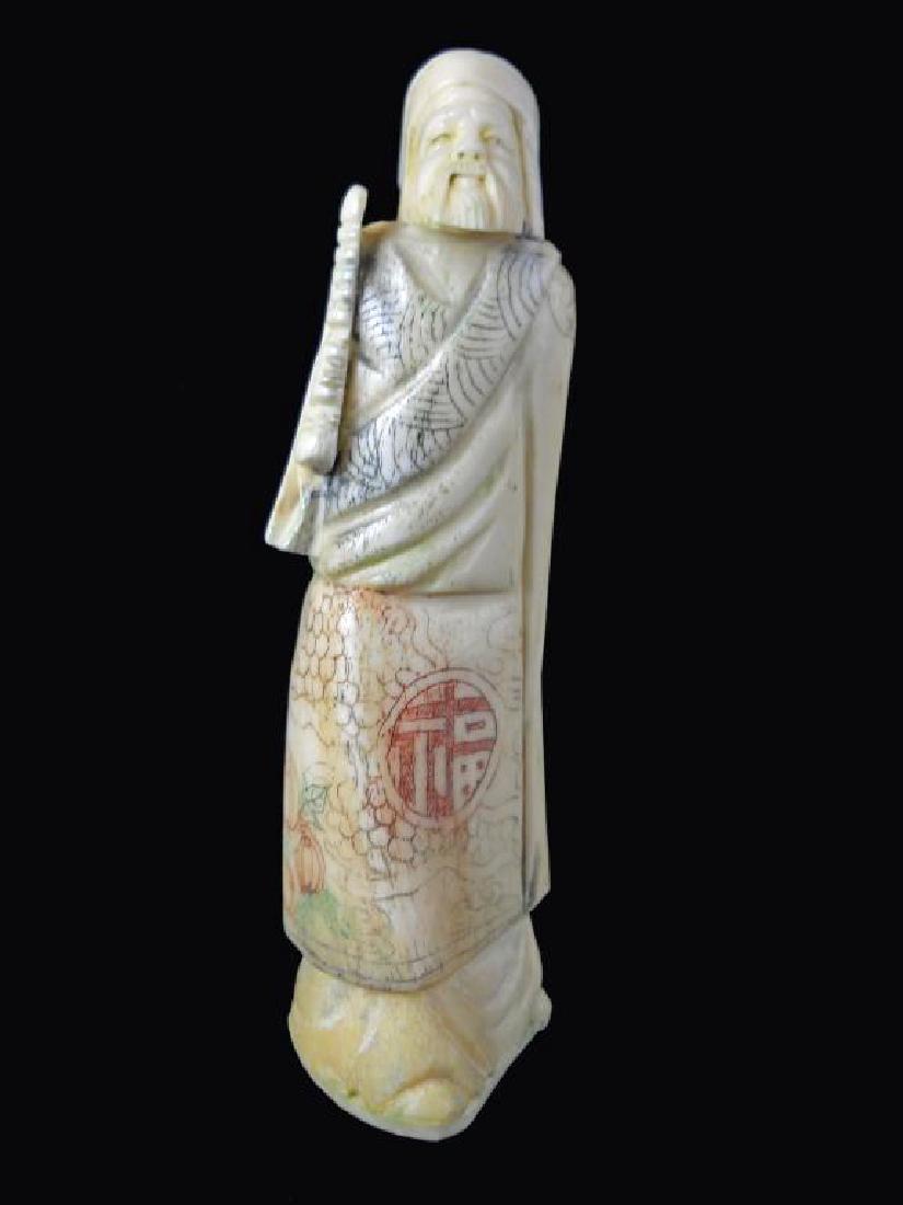 Antique Japanese Bone Okimono Figure: Large Japanese hand-carved polychrome bone okimono, figure of a scholar. His robe is colorfully embellished with symbols, patterns & fruit. He holds a staff in his hands. 7" H X 2" W X 2" D.