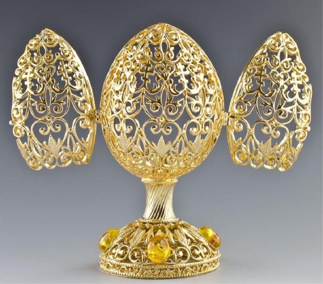 Faberge Inspired Rising Cross Egg Trinket Box: Gold gilt over pewter, crystal inlaid lattice work egg trinket display box, Faberge Inspired rising cross. Has 2 small doors that open to reveal display area for jewels or small objects. 5'' H X 2.5''