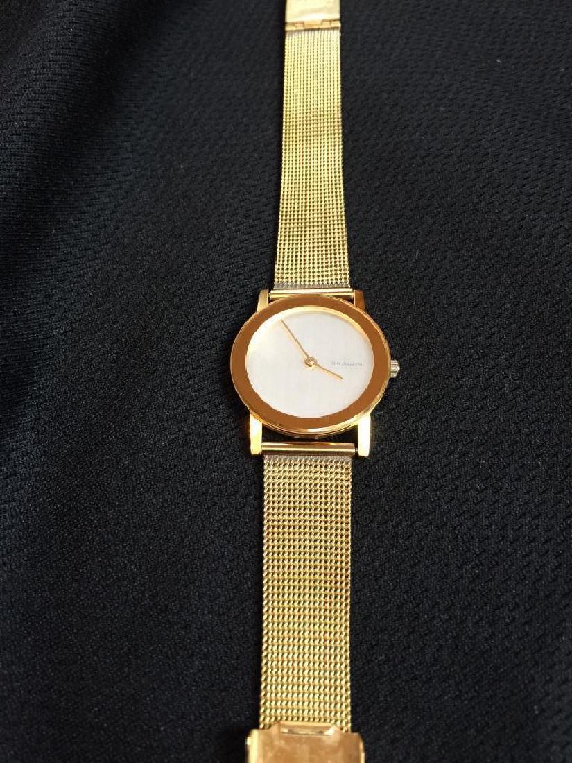 Ladies Contemporary Gold Skagen Watch: Skagen Denmark 39SGG Ultra Slim. Japan quartz movement. Stainless steel gold mesh band. White face with gold hands. Modern styling. In very good condition. Needs replacement battery.