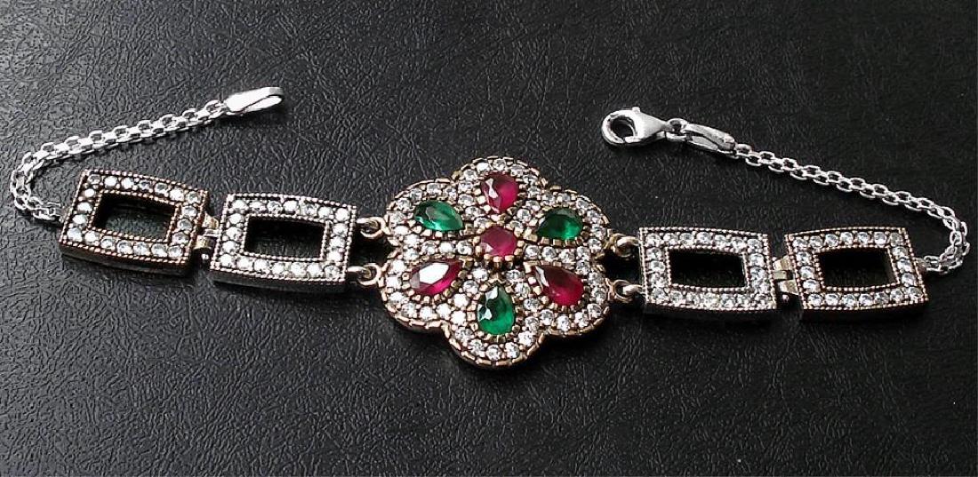 13.46ctw Ruby & Emerald Bracelet: Three pear cut faceted rubies & three pear cut faceted emeralds, with a small round cut ruby center stone, set into a floral style Turkish bracelet. 13.46cts. Sterling silver with gold enhancement. 1 