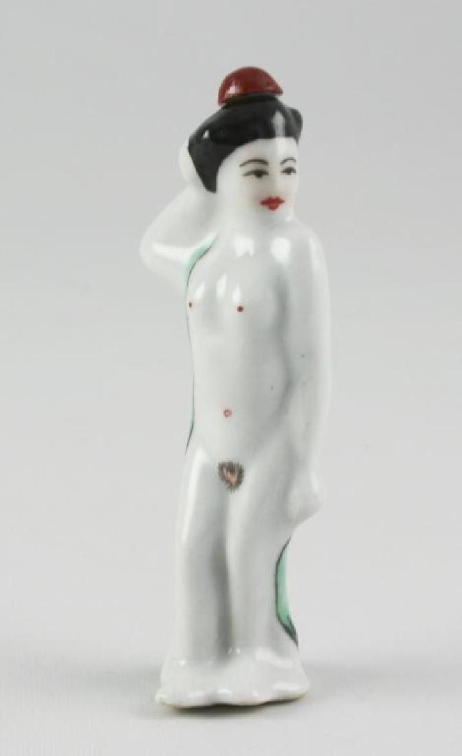 Porcelain Standing Nude Geisha Snuff Bottle: Chinese porcelain snuff bottle in the form of a nude geisha standing draped with a green sash. Red, black & green over-glaze. The top on her head is a stopper. Signed on the bottom by the artist. 3.6"