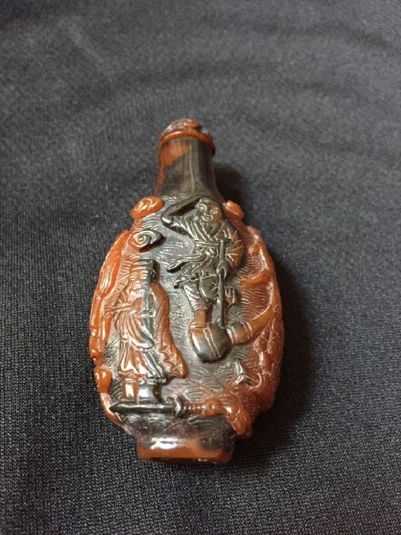 Chinese Monks Carved Snuff Medicine Bottle: Carved snuff or medicine bottle depicting Chinese monks & wise men with baskets & birds. Carved material appearing like amber, top with bone spoon in tact. 3" H X 1 1/2" W X 7/8" thick.