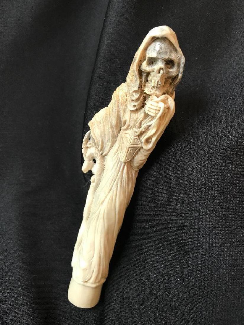Carved Antler Grim Reaper Skeleton Death Cane Handle: Hand-carved shed deer antler, in the form of The Angel of Death or Grim Reaper, skeleton. Walking stick or cane handle. Cloaked skeleton holding a lantern in one hand & a crooked staff in the othe
