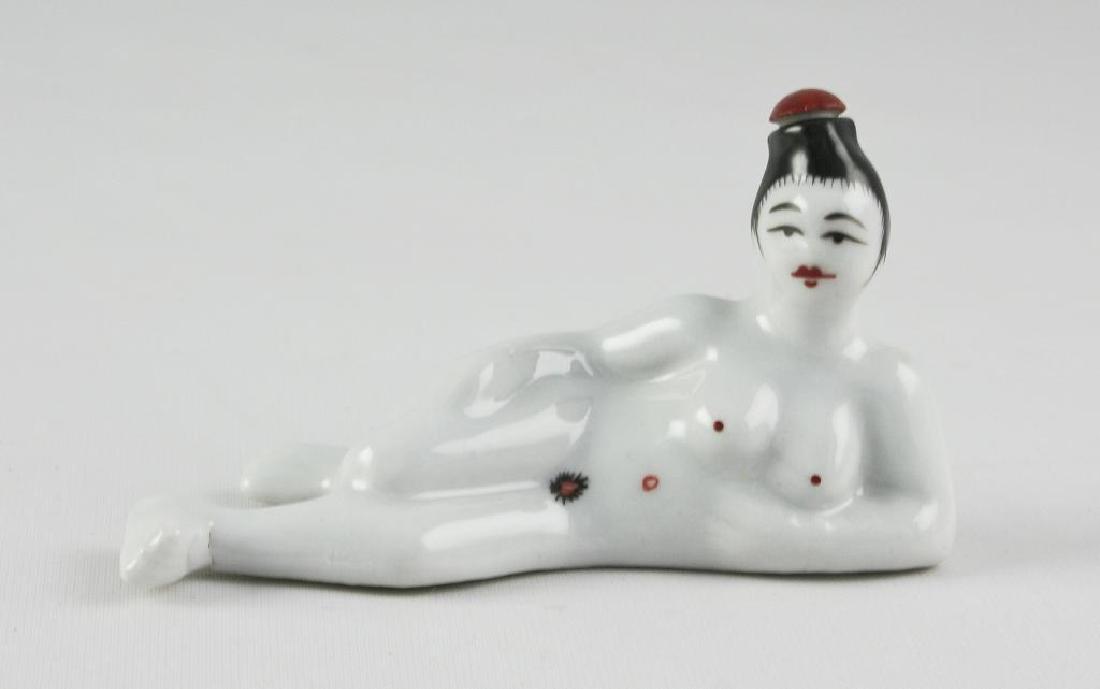 Porcelain Reclining Nude Geisha Snuff Bottle: Chinese porcelain snuff bottle with red & black over-glaze depicting a nude, reclining geisha. 3 1/2" L X 2" H. The red top on her head is a stopper. Fantastic little bottle. Signed on the bottom 