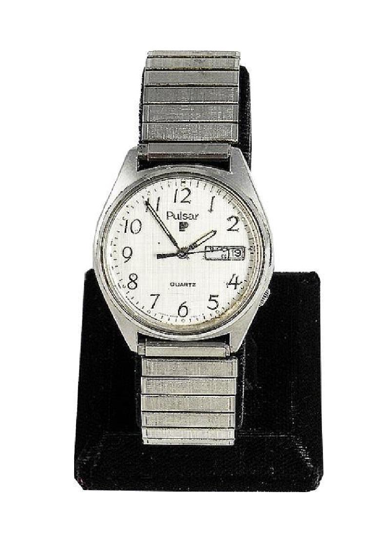 Vintage 1980's Men's Pulsar Quartz Fashion Watch: Men's Pulsar brand with stainless steel stretch band. Light silver colored face with black numbers & dials. Day & date on right side of face. Water resistant. Used condition, with light scratc