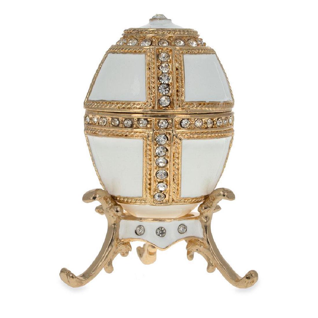 1890 Danish Palaces Faberge Egg (White): 1890 Danish Palaces Faberge Egg (White) 2.75 Inches Tall Enamel Gold Plated Pewter, Austrian Crystals Hand Painted Padded Satin Lined Gift Box Imported This sparkling egg is adorned with clear crystal