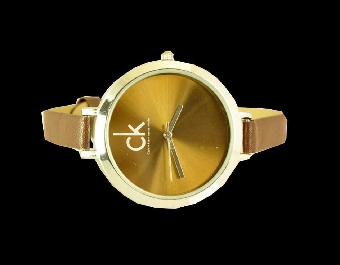 Calvin Klein Copper Tone Wristwatch: Water resistant stainless steel case. Copper tone face with CK logo & smaller letters that read Calvin Klein Swiss made. Quartz movement. Stainless steel hands. brown faux leather strap. New store sto