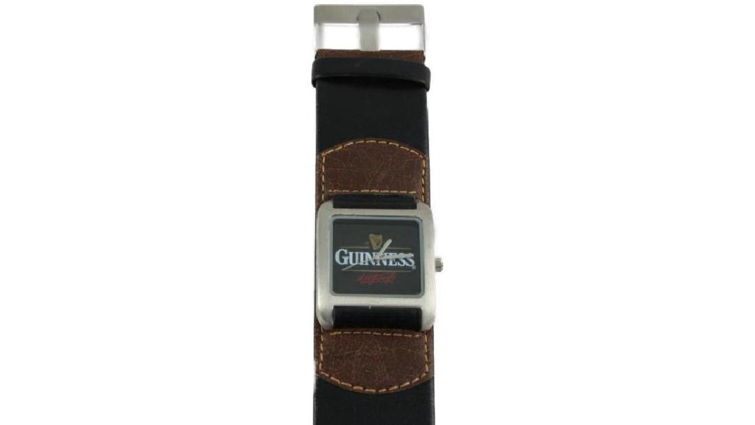 Men's Guinness Stout Advertising Watch: Men's Guinness memorabilia analog watch with black & brown leather band, stamped with Guinness harps & the tm Guinness stamped on the end. Face is an unusual square stainless steel black face, with Gu