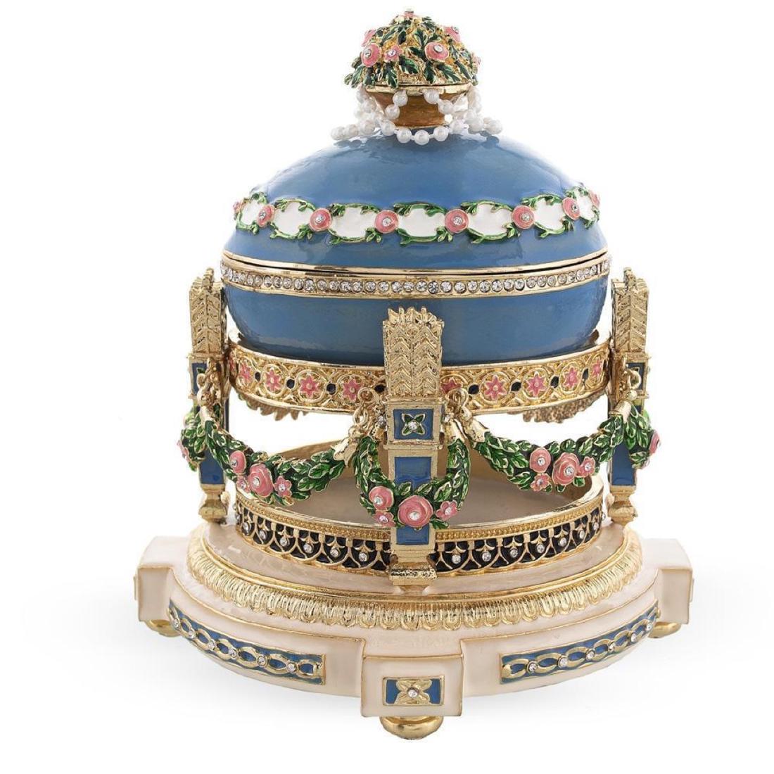 1907 Love Trophies Egg (Cradle with Garlands) Royal: 1907 Love Trophies Egg (Cradle with Garlands) Royal Russian Egg 5.8 Inches Tall (on a stand) x 5.3 Inches Wide 14.732 cm Tall (on a stand) x 13.462 cm Wide Enameled Gold Plated Pewter Hand Painted Pla