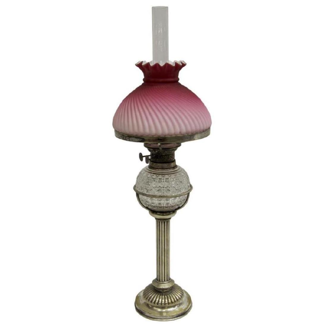 English Silverplate & Cut Glass Standing Oil Lamp: Hukin & Heath silverplate standing oil lamp, Birmingham, fitted with a cane-cut glass font, wick burners marked Martins Patent, colorless hurricane shade with loss at base, a swirled pink to white cas