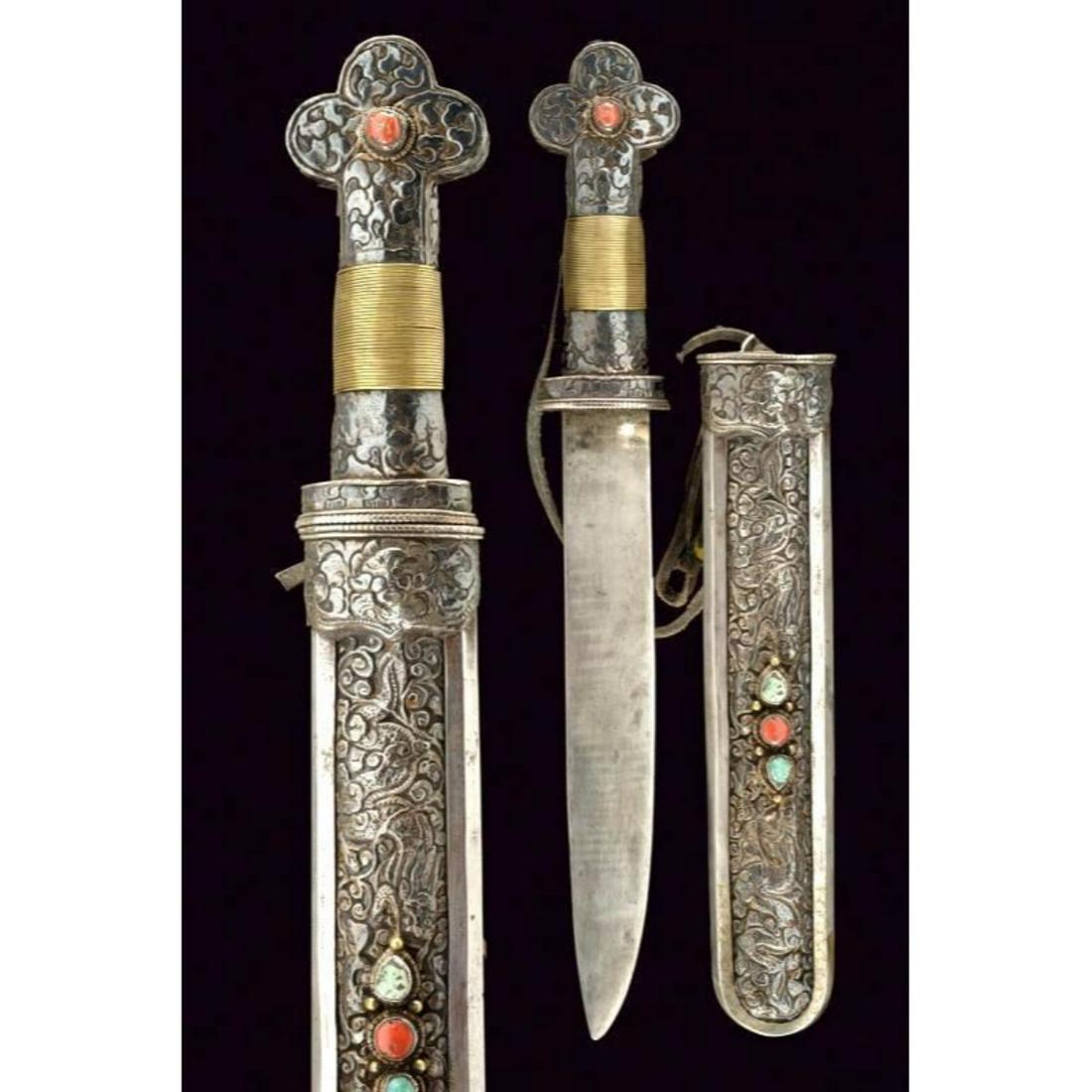 19thc. Ornate Tibetan Dagger: 19th Century Tibetan dagger with wide straight blade with a thread. Supply covered with silver foil finely engraved with floral motifs, the clover-pommel with cabochon coral, the handle covered with b