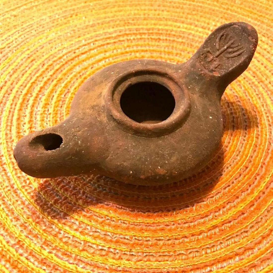 Handmade Clay Oil Lamp, Menorah: Handmade clay ancient-style oil lamp, the handle impressed with a Menorah symbol. * this was one of a collection of oil lamps with no information or provenance. 5 3/4" L X 3 1/4" W X 1 3/4" H.