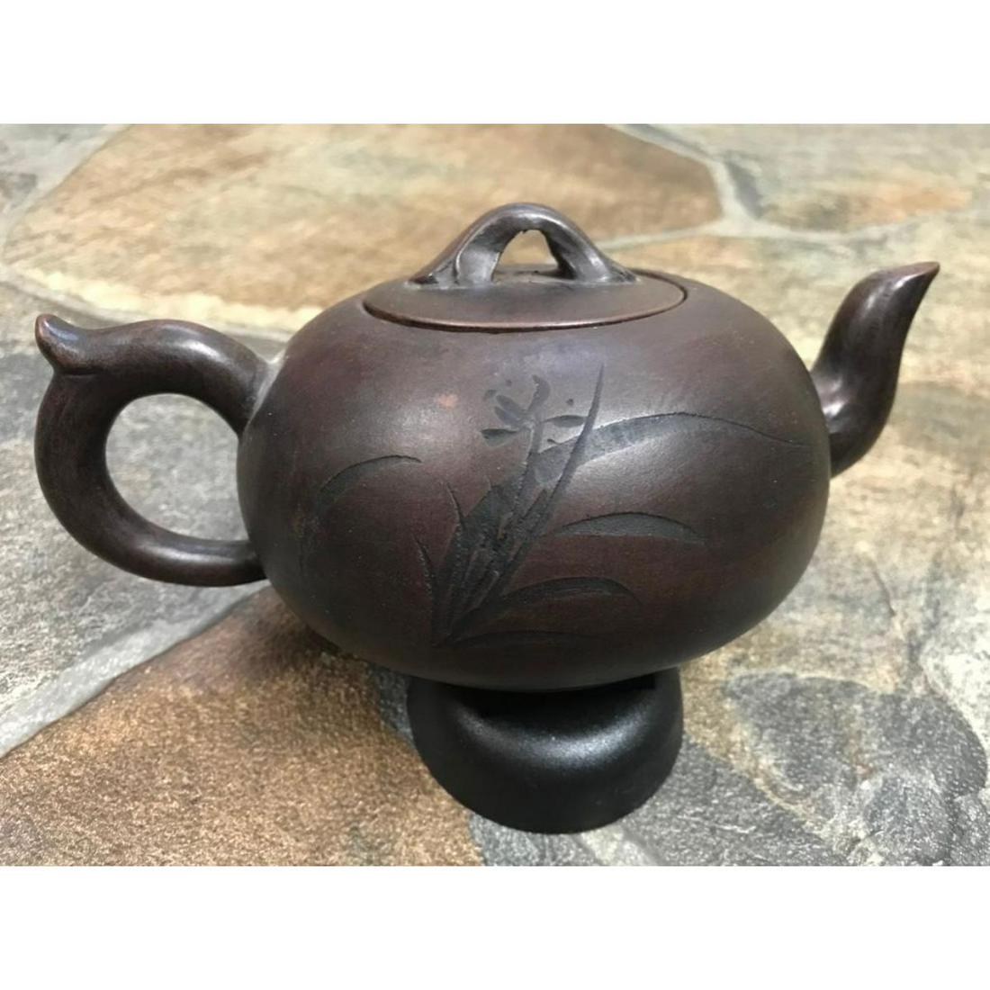 Chinese Yixing Clay Teapot: Chinese purple yixing clay teapot with floral scene on one side & characters on the other side. Signature stamp on bottom. 7" L X 4 1/2" W X 3 1/4" H.