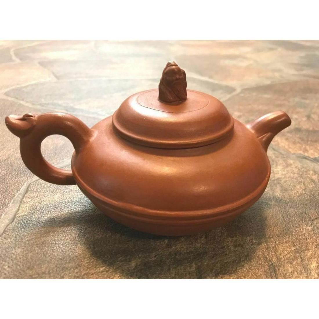 Yixing Clay Scholar Teapot: Japanese purple yixing clay teapot, with characature scholar as the top of the lid. Smooth around the sides. Artist, manufacturers seal stamp indent to bottom. Also an inventory or collection number a