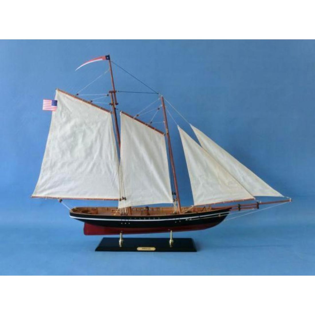 Wooden America Model Sailing Ship: Wooden America model sailing ship with cloth sails & two flags. On stand with metal nameplate. 35" L X 6" W X 28" H (1:38 scale).