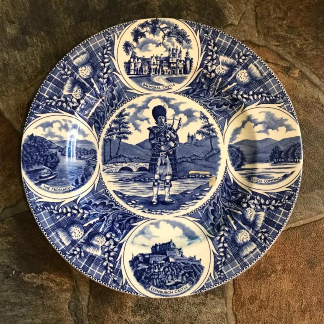 Vintage Scottish Pride Weatherby Collectible Plate: Vintage Scottish Pride, blue and white, collectible, decorative plate made by J.H. Weatherby & Sons, features a piper in traditional Scottish Highland dress, surrounded by a thistle border and picture
