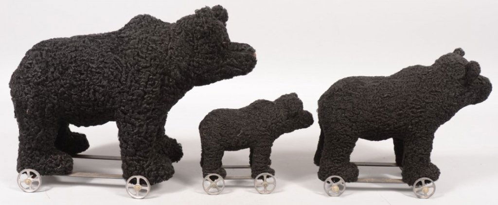 Three Graduated Toy Black Bear Pull Toys. Strap ir: Three Graduated Toy Black Bear Pull Toys. Strap iron frame with four cast tin spoked wheels. Bears have a curly lamb coat with brown thread nose and glass eyes. All signed on front paw pads: inM.E. Be