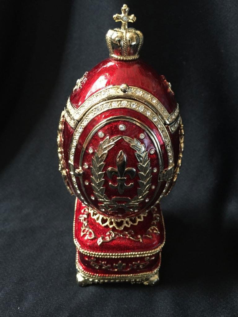 Faberge Inspired Guilloche Egg Frame Jewel Box: Faberge-Inspired trinket jewel box egg. Guilloche enamel over pewter. Fleur-de-Lis secret treasure hatch at the top with hidden oval 1" X 2" picture frame opening in the front. Base has an magnet to h