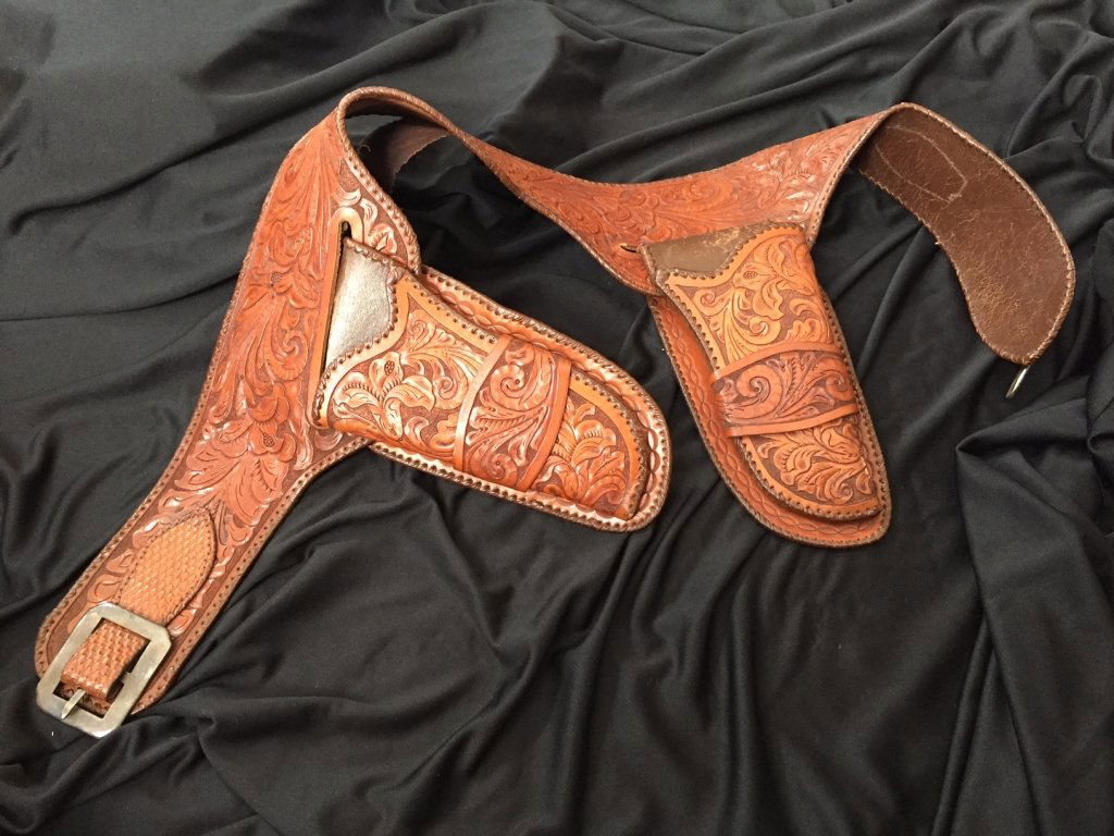Colt Double Holstered Gun Belt with Silver Buckle: 20th century fine elaborately tooled Western double holster for single action Colt Pistols. Worn condition with some inside leather lining issues. Some scratching & wear to the top section of the hols