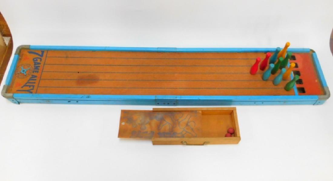 7 GAME ALLEY: WITH 10 PINS AND 2 BALLS. 47" LONG, RISES TO 17 3/4" TALL. ONE LEG SUPPORT IS NEEDS REPAIR.