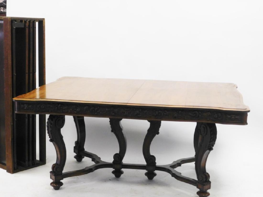 CARVED WALNUT DINING TABLE: WITH FOUR ADDITIONAL LEAVES TOP IS 65" LONG X 50" WIDE. HAS A 4 LEG BASE WITH STRETCHERS AND SUPPORTS MINOR BLEMISHES TO TABLE TOP