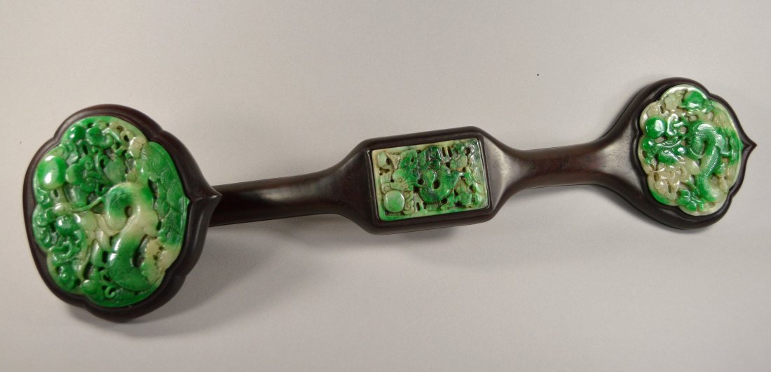 A QING JADEITE RUYI SCEPTER: A stunning qing jadeite ruyi scepter with wood handles, finely carved jadeite inserted at the ends and the middle, with dragons, lotus, bat and ruyi, wooden handle probably later 20th century. Size 20